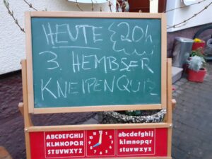 Vor dem Herzog steht eine Tafel mit der Aufschrift "Heute 20h Hembser Kneipenquiz".